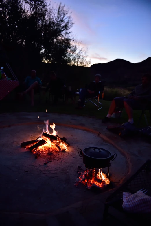 several people sitting in the evening near a fire pit