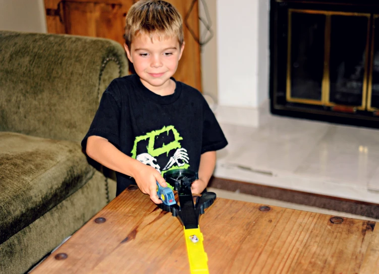 a  holds a yellow object in front of a wood table