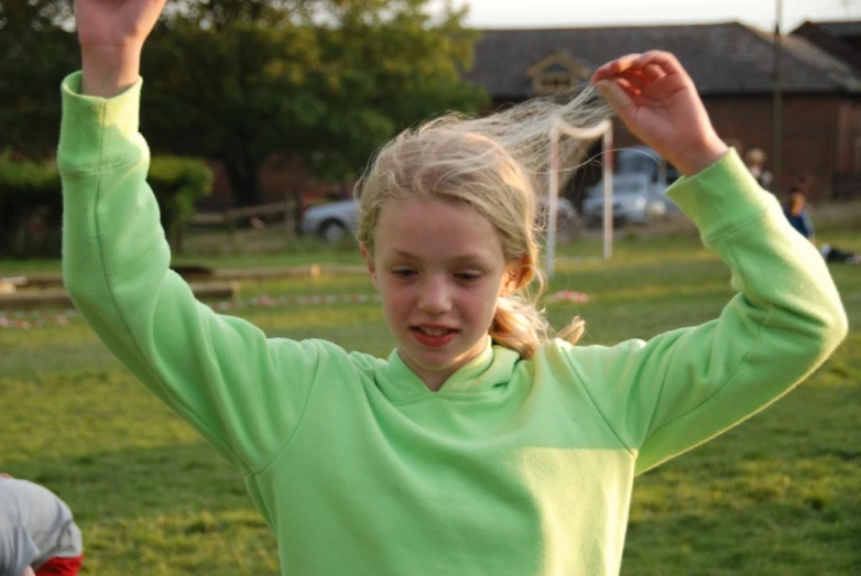 a  is playing outside with her hands raised