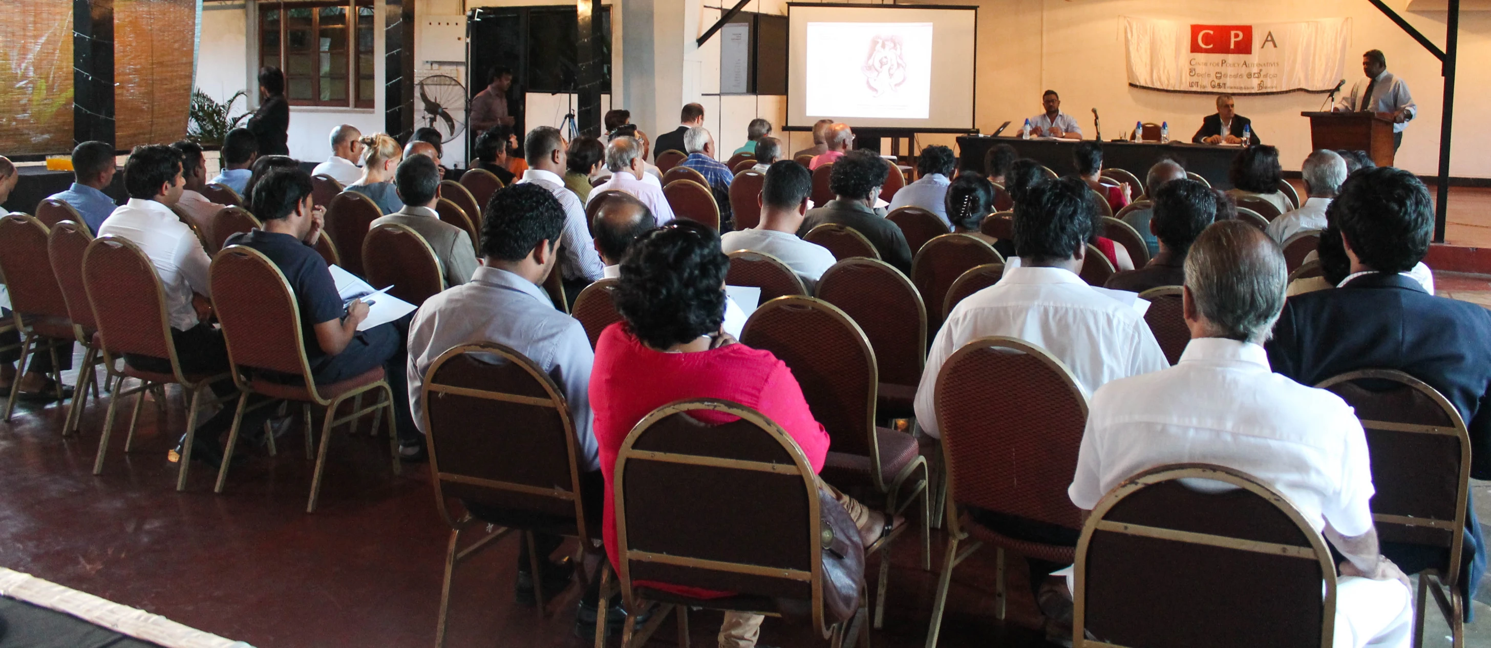 large group of people sitting in chairs and listening to the speaker