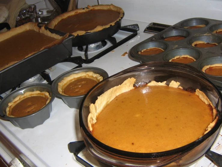 pumpkin cheesecake sitting in front of many pans on the stove