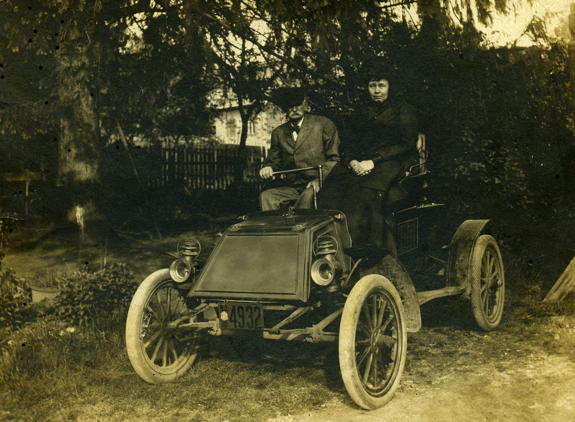 a group of men are standing in front of an antique car