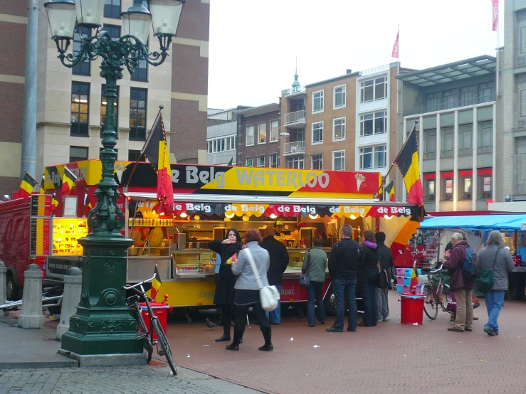 people are walking around the food stand with flags