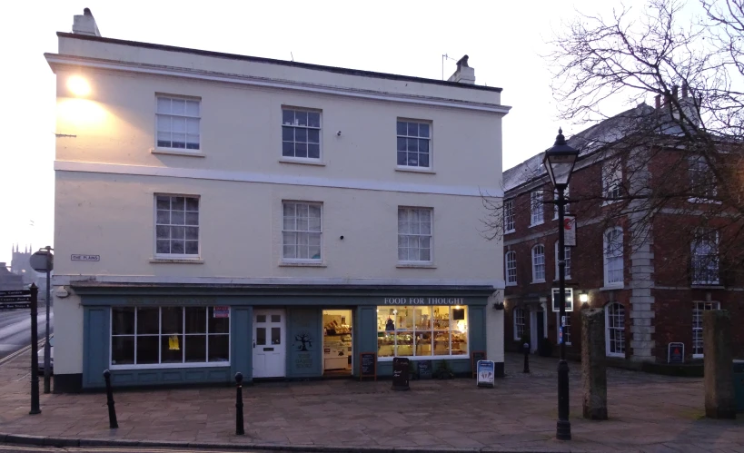 an empty sidewalk outside a building with a shop front