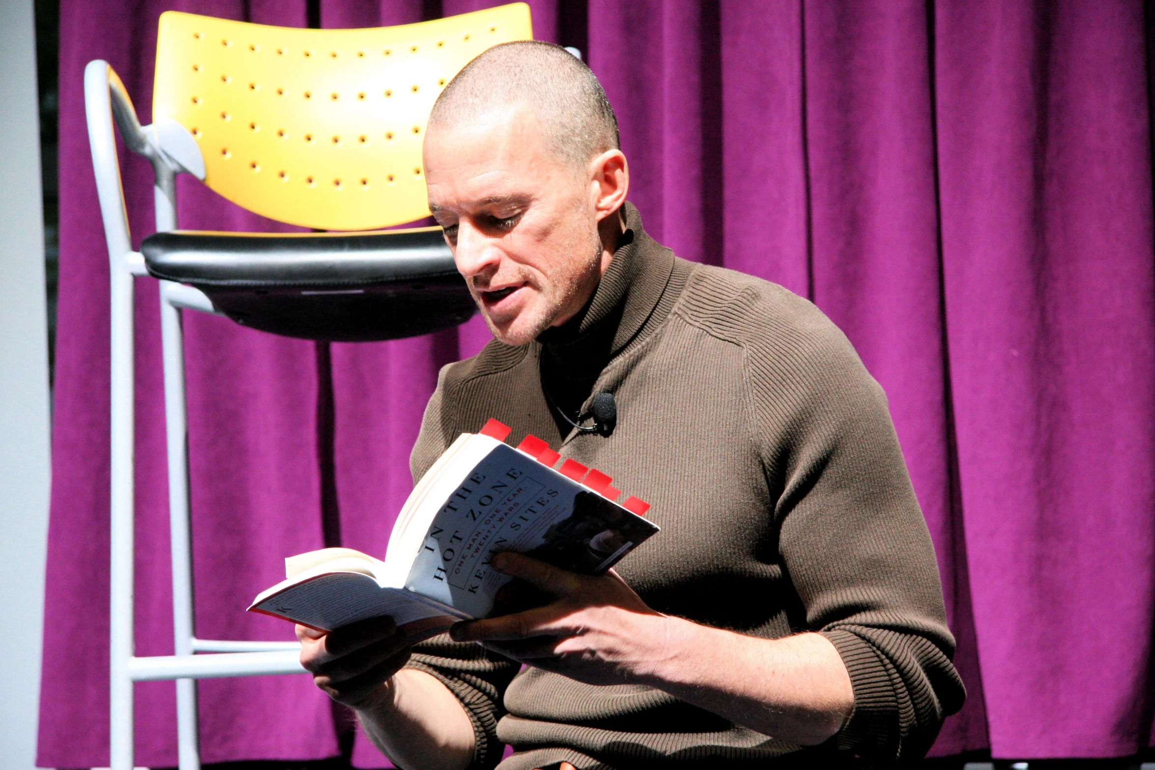 a balding man is reading in a chair