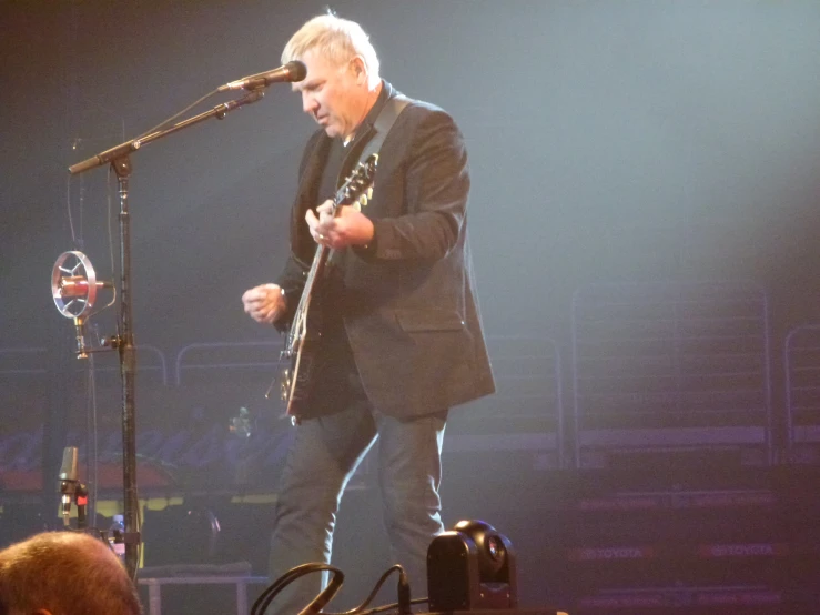 a man standing at a microphone in front of a band