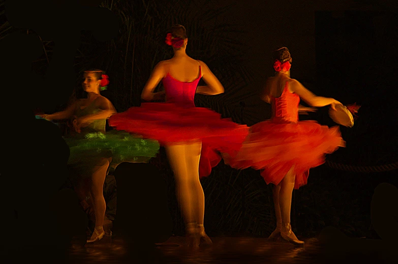 three ballerinas in neon dresses perform on stage