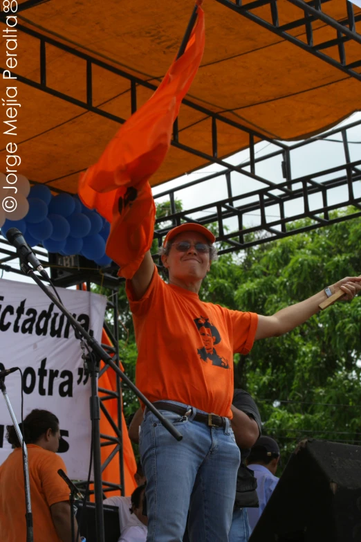 a person is standing at a stage with an orange scarf