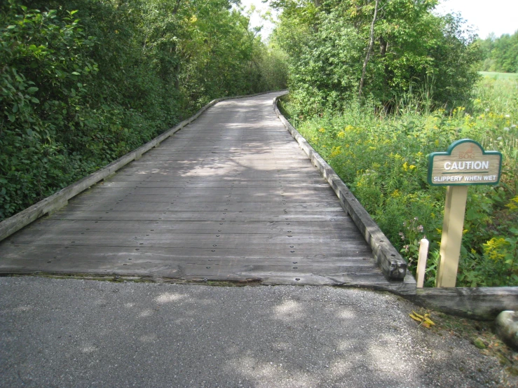 an empty wooden walkway with trees surrounding it