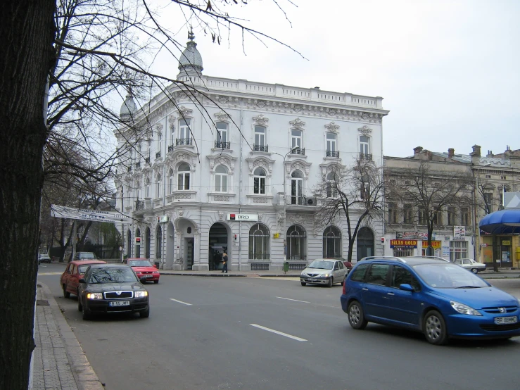 two cars driving past an old building on the road