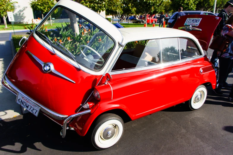 small red car with white painted hood parked on street