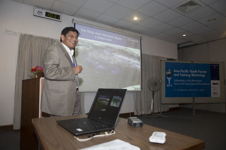 a man stands in front of his computer and gives a presentation