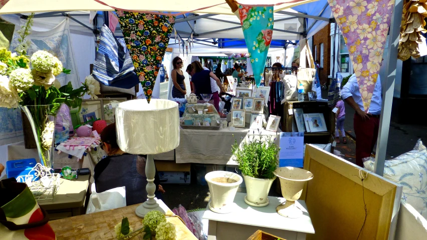 some people are standing near a booth selling crafts and goods