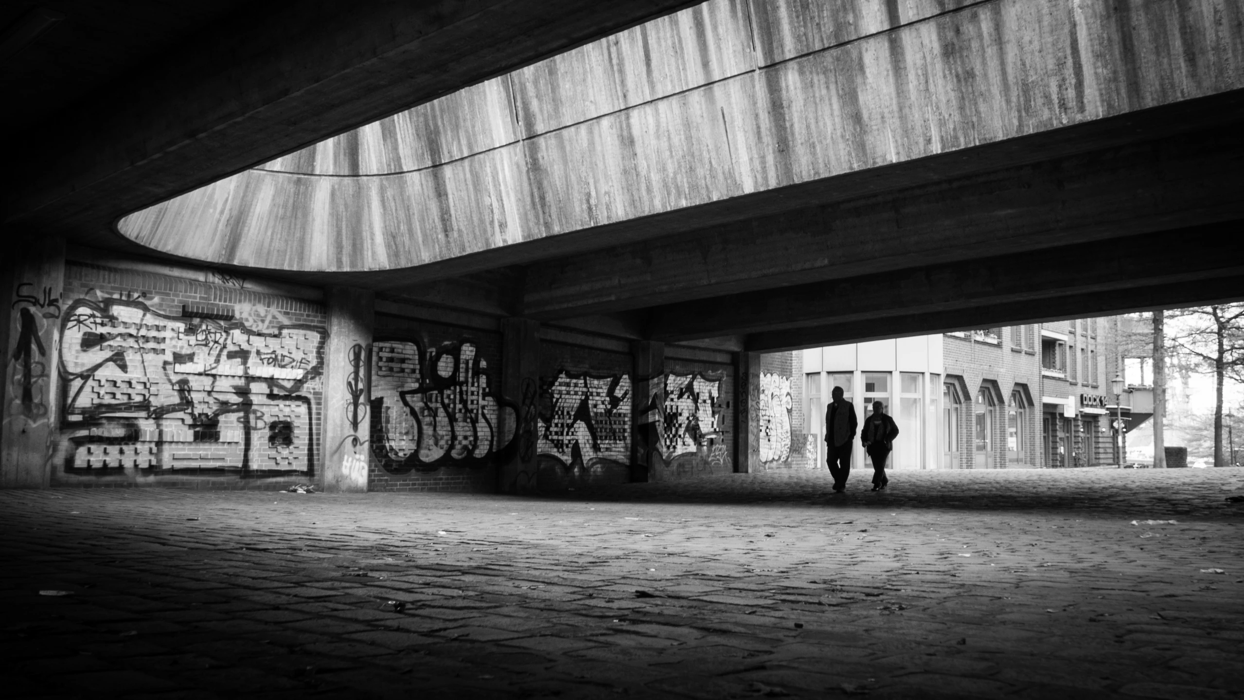 two people standing under a very large overpass