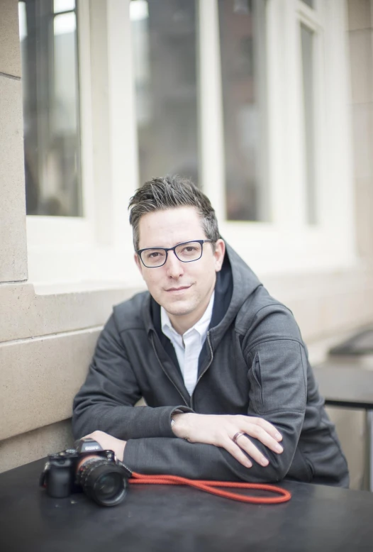 a man in glasses is leaning on a table holding an object