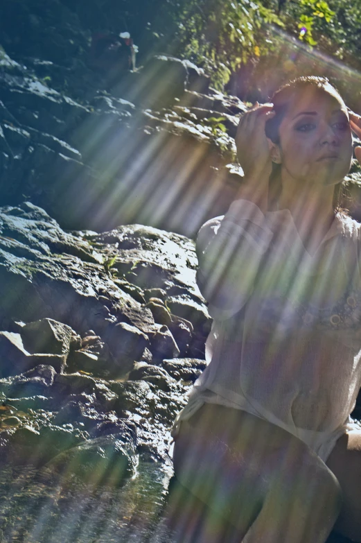 a beautiful young woman posing on the side of a mountain