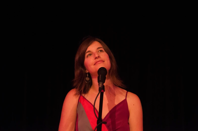 a woman is standing at a microphone with her eyes closed