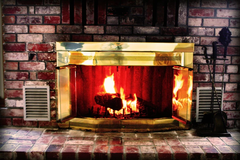 a fireplace with flames lit next to a brown brick wall