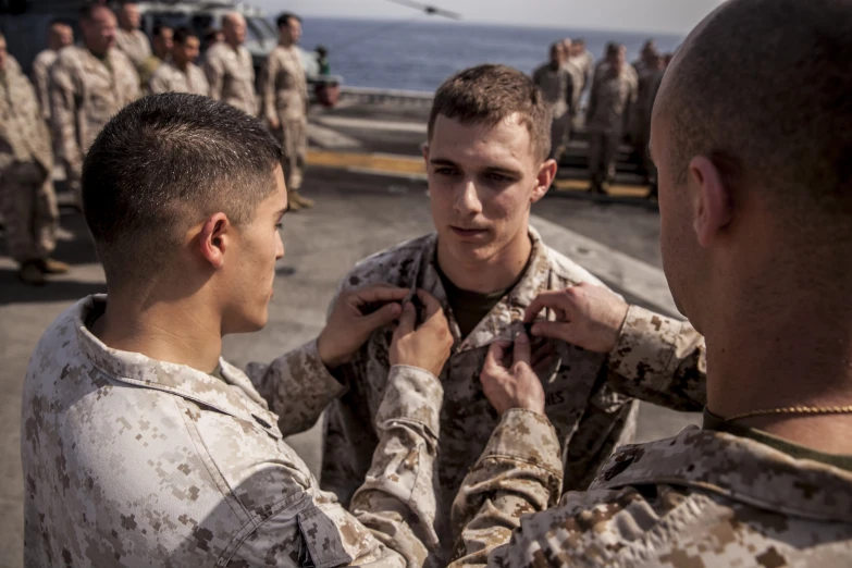 soldier pinning another soldier's medal on his uniform