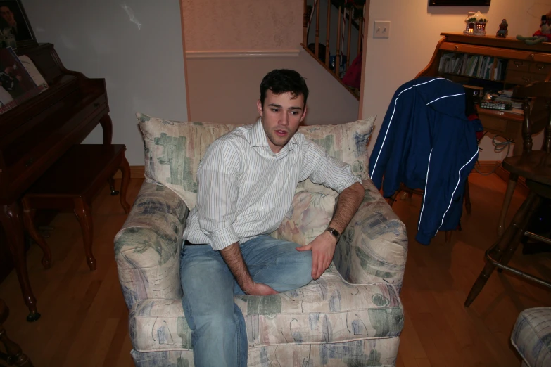 a young man sitting in a chair next to a stair case