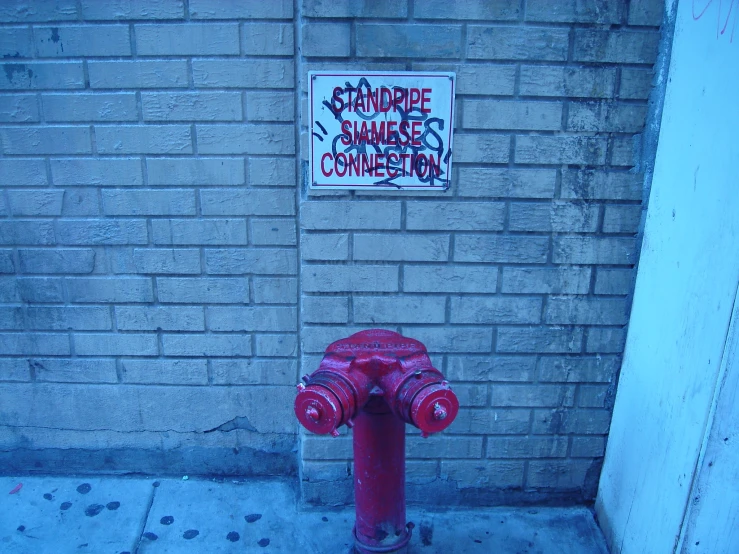 a red fire hydrant on a sidewalk next to a sign