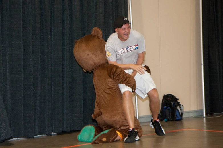 man with bear mascot in a gymnasium with other people