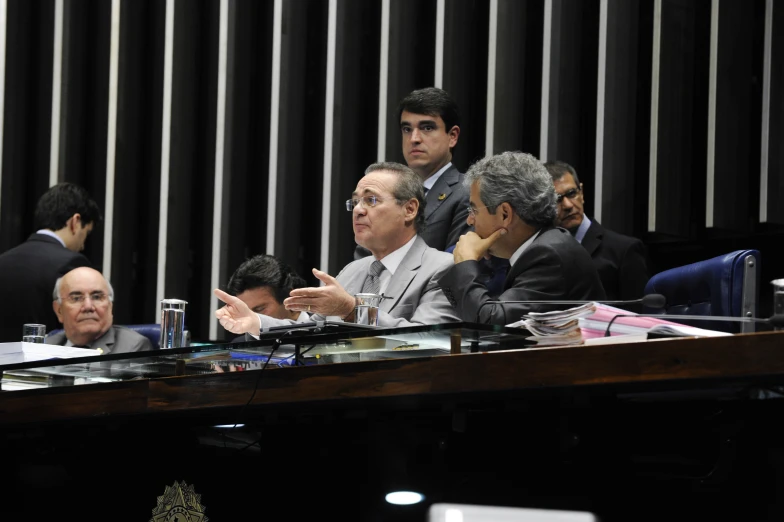 men in suits are sitting on the table while they talk