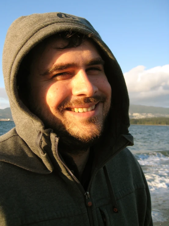 the man is standing at the ocean shore smiling