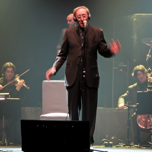 a person singing with another musician on stage behind him