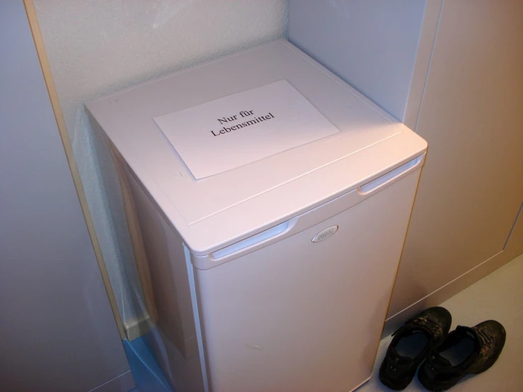 a small fridge with shoes on the floor