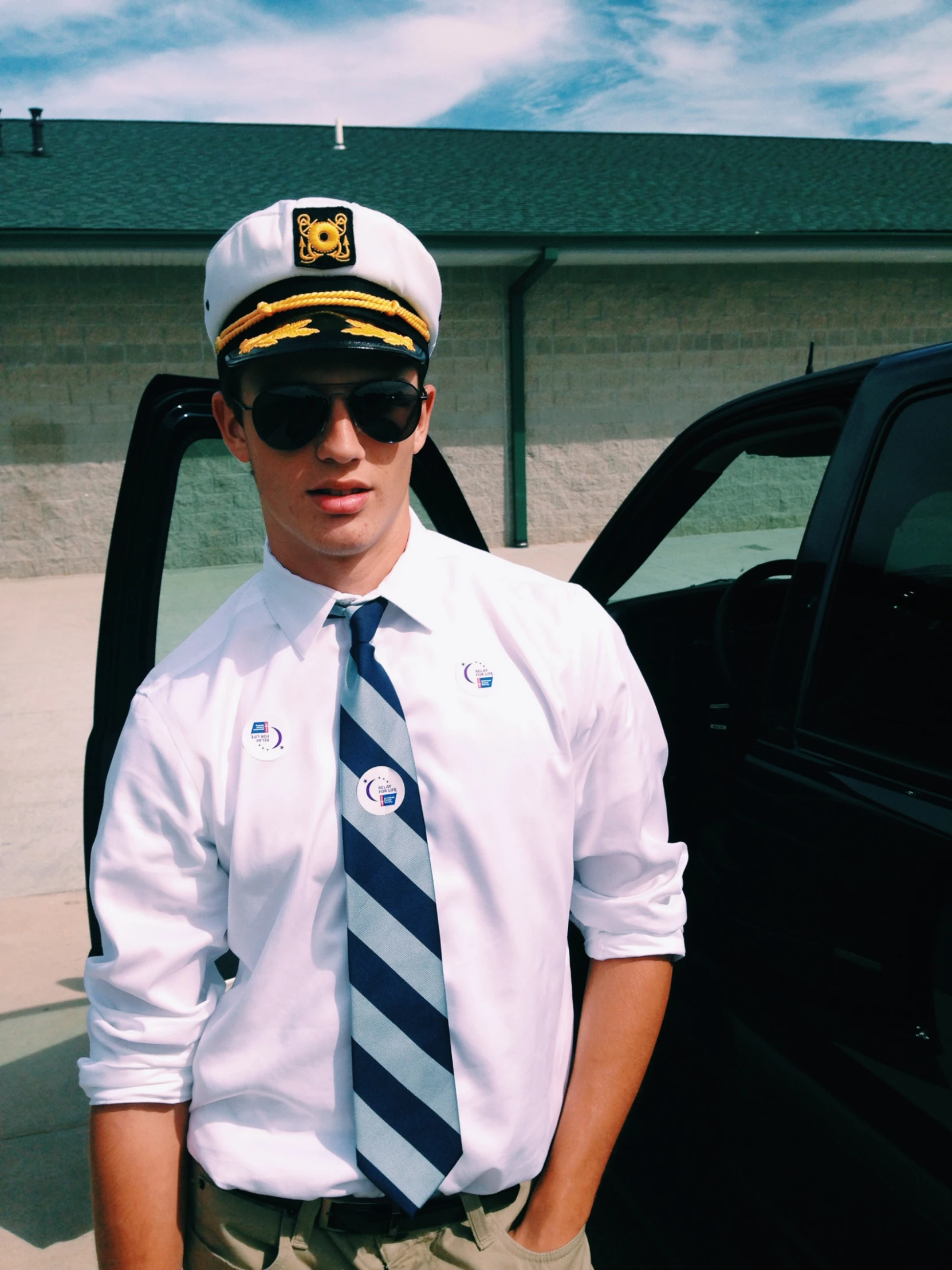 a man in a white shirt wearing glasses and a navy hat