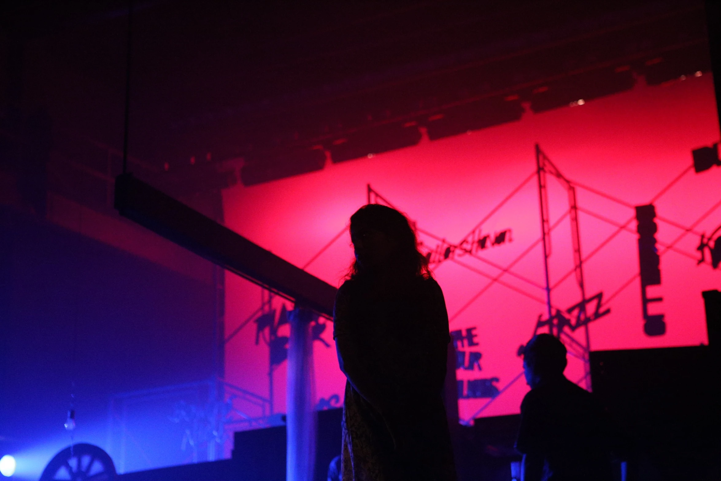 two people standing in front of a stage with some colored lights