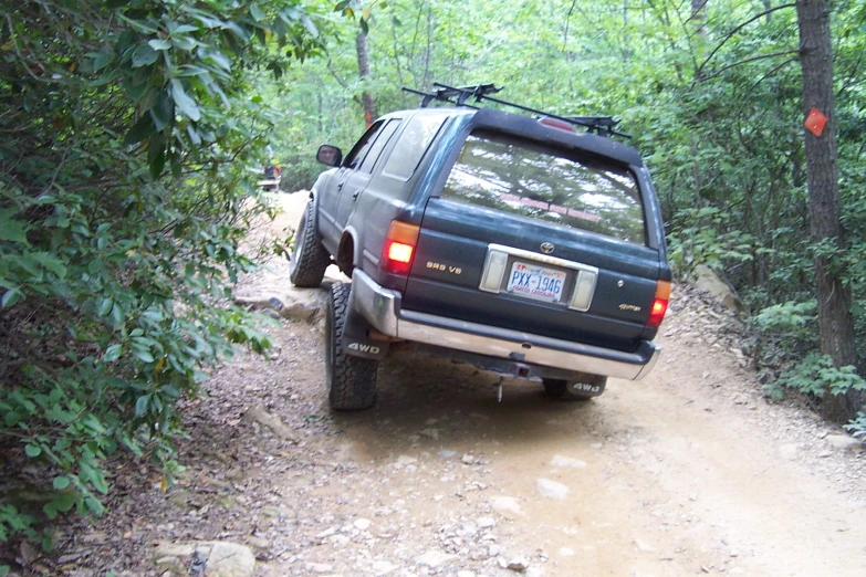 truck traveling up a trail through the woods