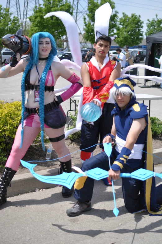 three anime cosplayers are standing with various props