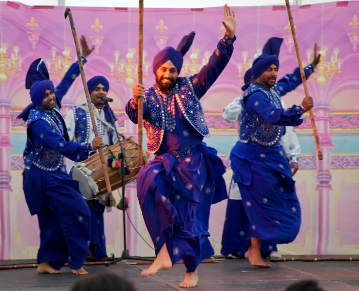 a man in blue and purple suit dancing with other men