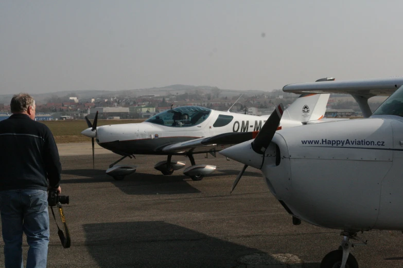 people standing near two small air craft sitting on a tarmac