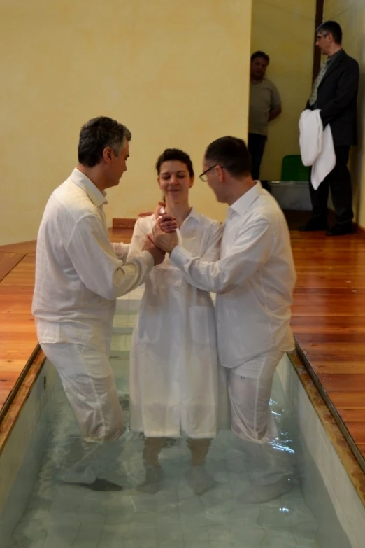 two men in white bathrobes hold hands to their chests