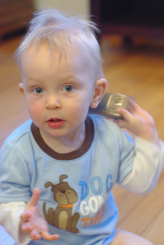 a toddler sitting on the floor playing with a cellphone