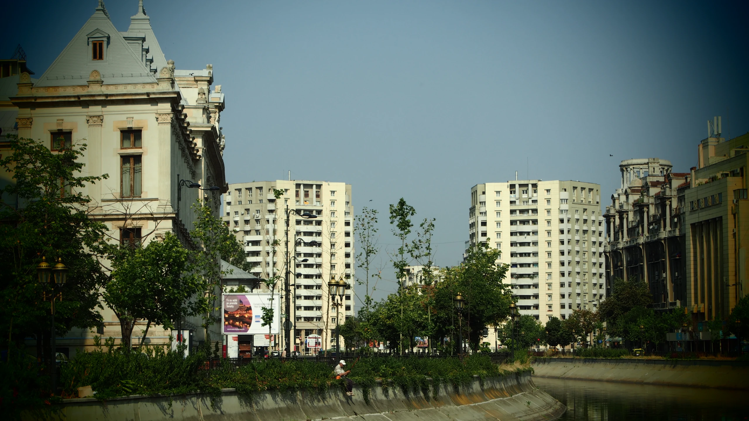 buildings along a river in front of trees and people