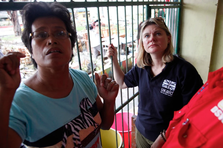 two women standing near each other in front of a gate