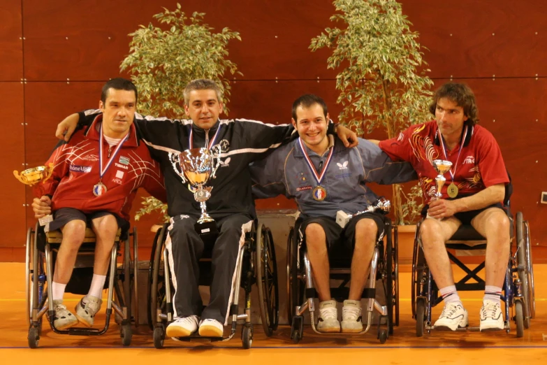 a group of men sitting in wheelchairs holding trophies