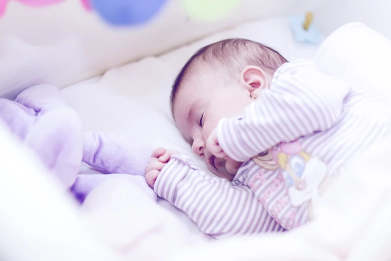 baby sleeping in crib with hand on baby doll