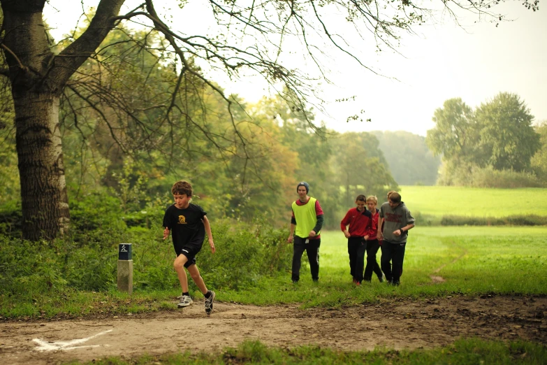 a group of men in various costumes running near some trees