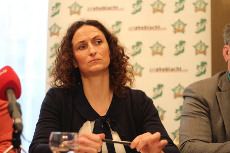 a woman holding a wine glass during a press conference