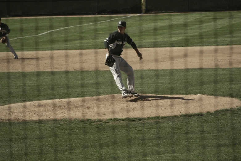 a baseball player pitching a ball on top of a field