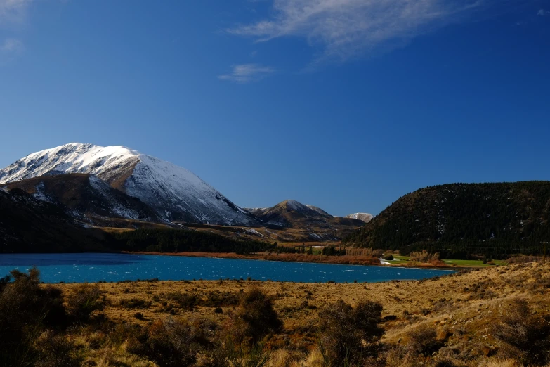 a view of a lake surrounded by mountains and fields