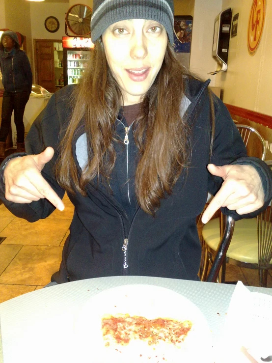 a woman with long hair standing in front of a plate of pizza