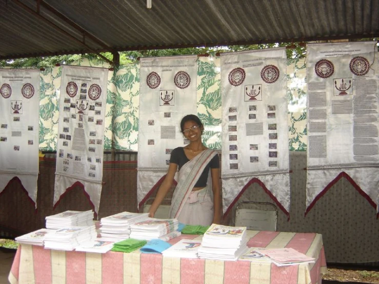 a woman standing next to a table with some pamphlets