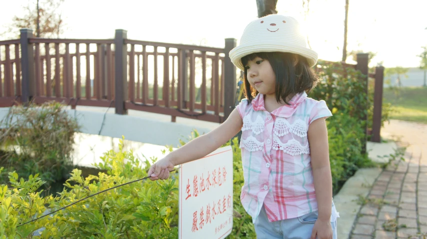 a little girl holding a sign with a helmet on her head