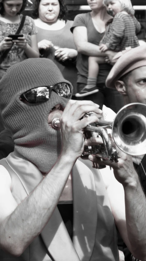 a man with a hat and sunglasses on, playing a trumpet